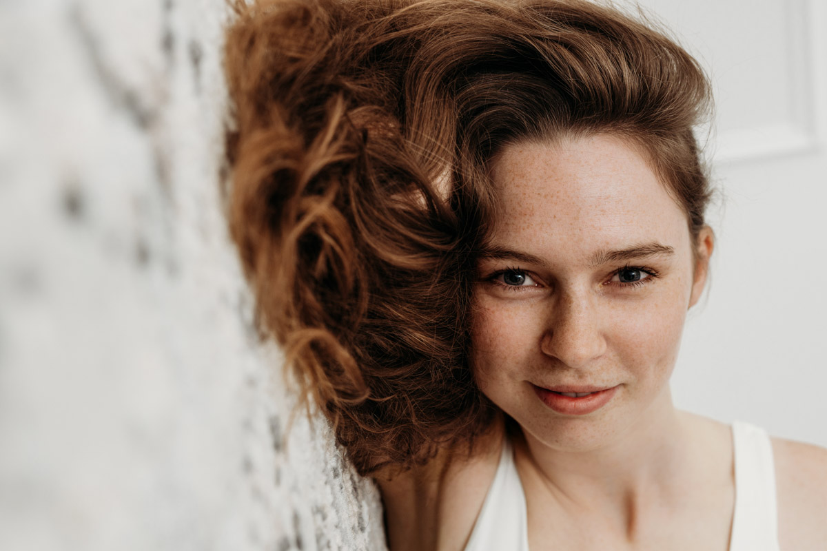 Portrait von rotem Lockenkopf mit Sommersprossen und vollen Lippen