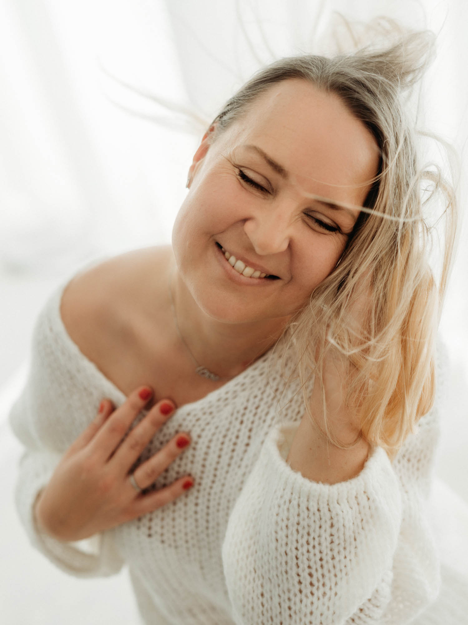 Frauenfotografie lächelnde Frau im hellen Strickpullover.