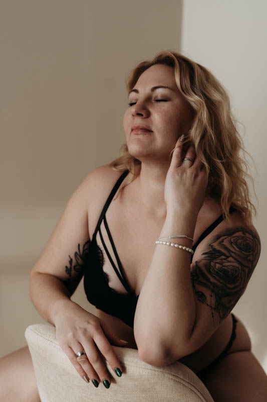 Selbstfürsorge einer Frau mit lockigem Haar beim Boudoir Fotoshooting
